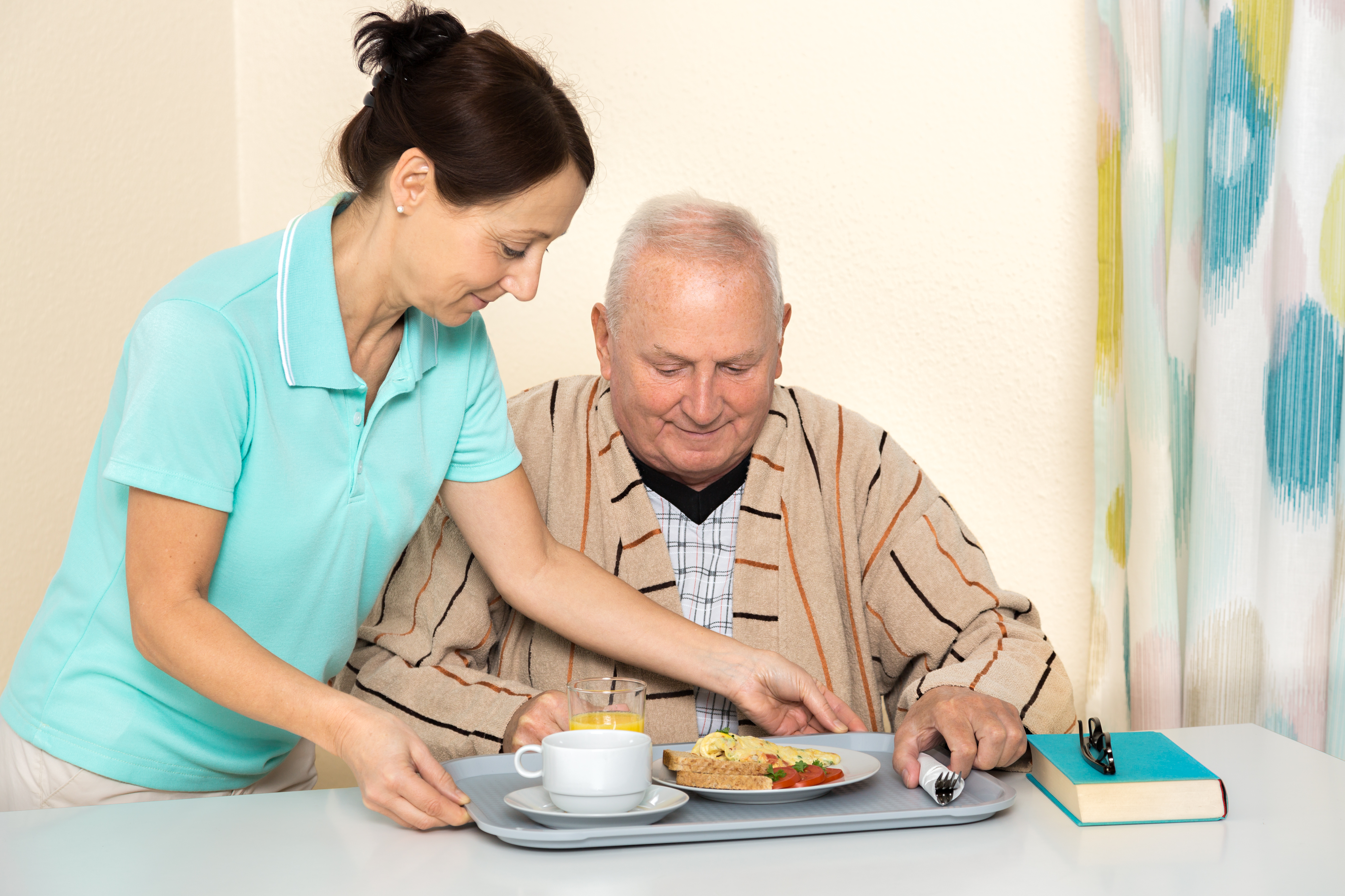 Senior man with home carer having breakfast